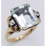 A 10K Yellow Gold Aquamarine and Diamond Ring. 8ct rectangular cut central aquamarine with two