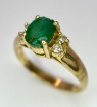 A 14K Yellow Gold Emerald and Diamond Ring. Central oval cut emerald with two round cut diamonds