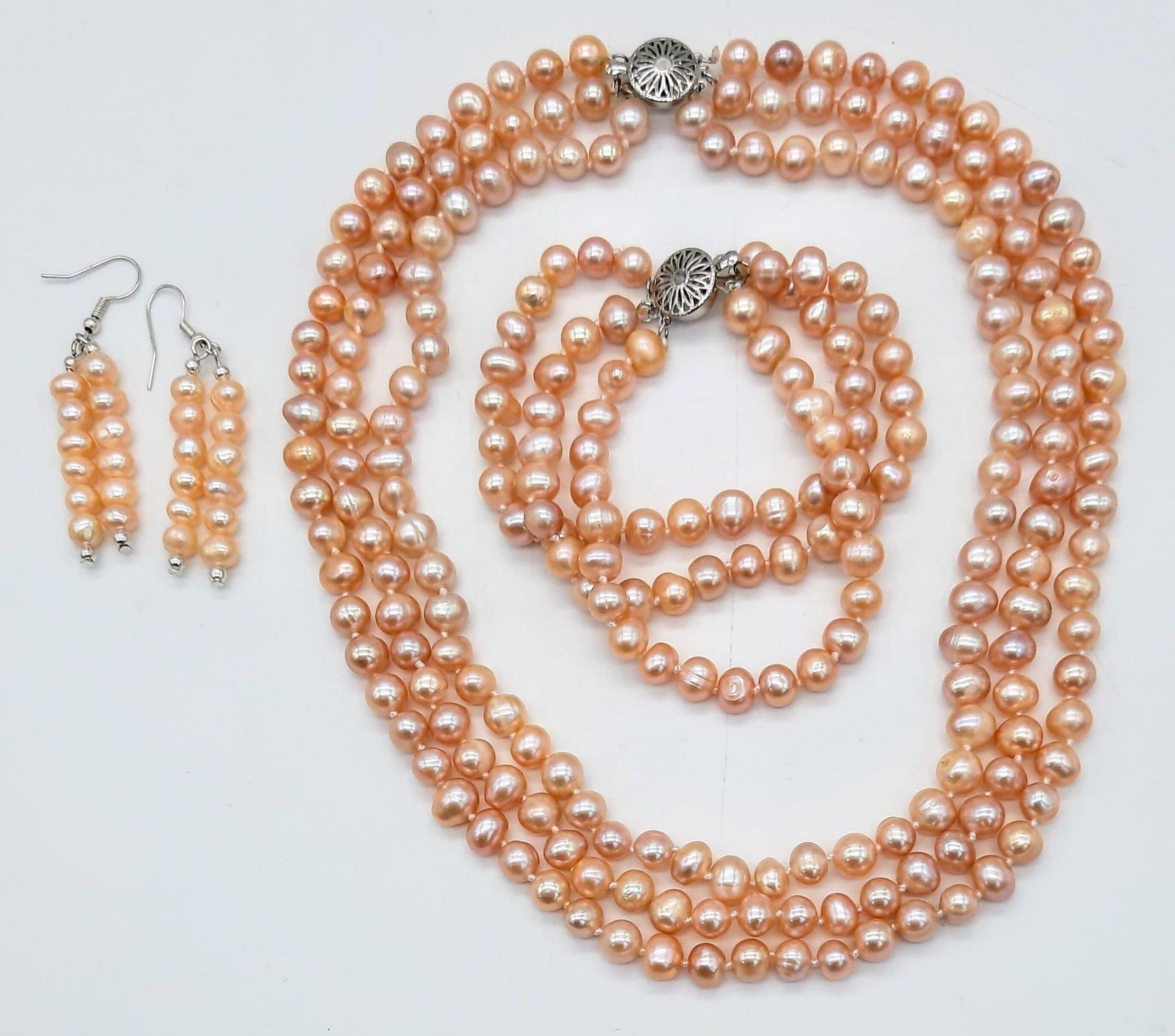 A fashionable three strand of high quality, natural pink pearls necklace, bracelet and earrings