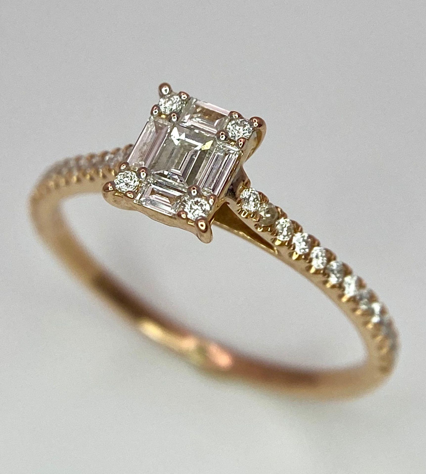 An 18 K rose gold ring with a square emerald cut diamond and more round cut diamonds on the