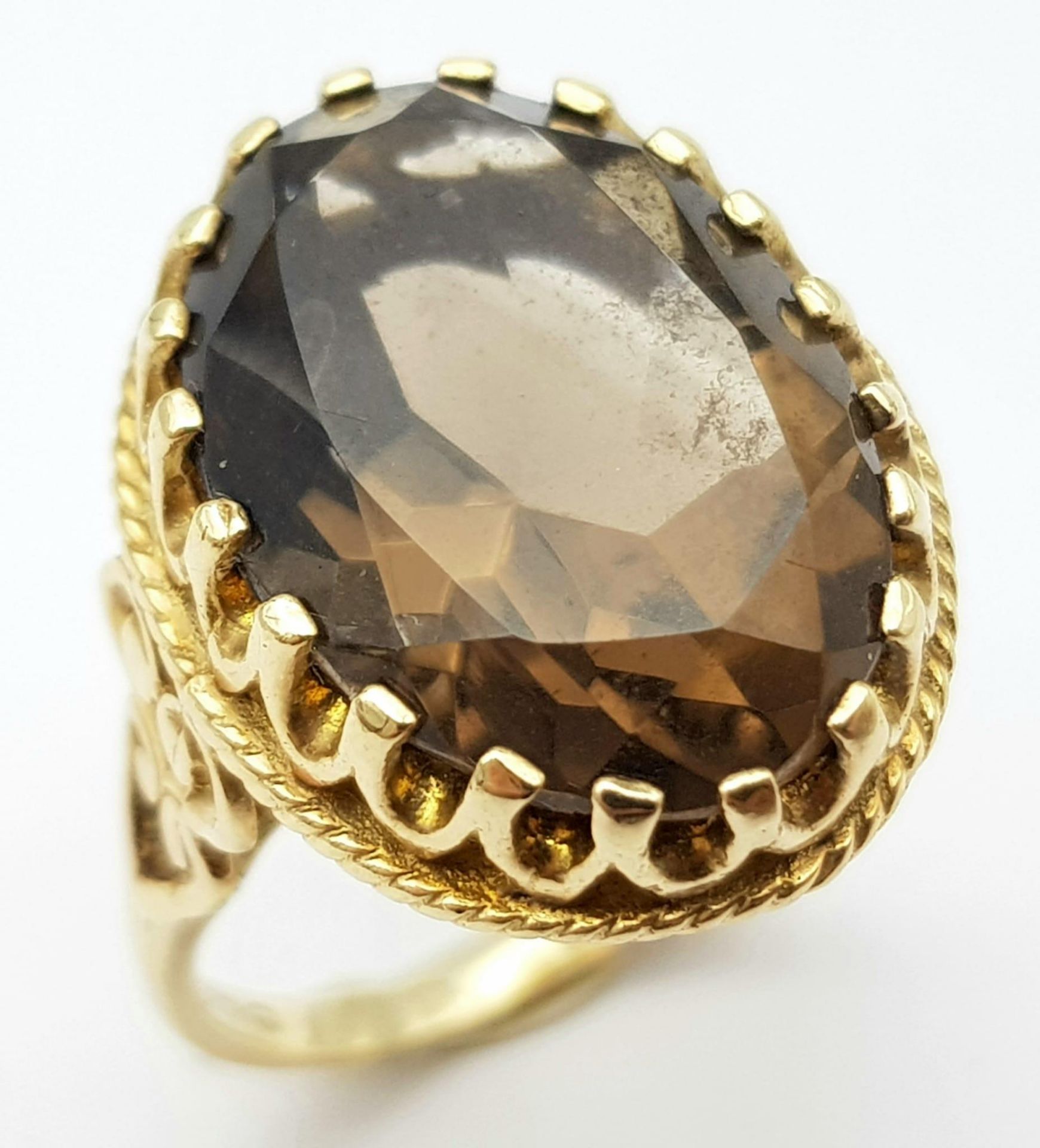 A Vintage 9K Yellow Gold Smoky Quartz Ring. Large oval cut 10ct smoky quartz in a decorative