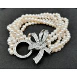 A fabulous six strand natural pearl bracelet with a large bow shaped clasp adorned with dozens of