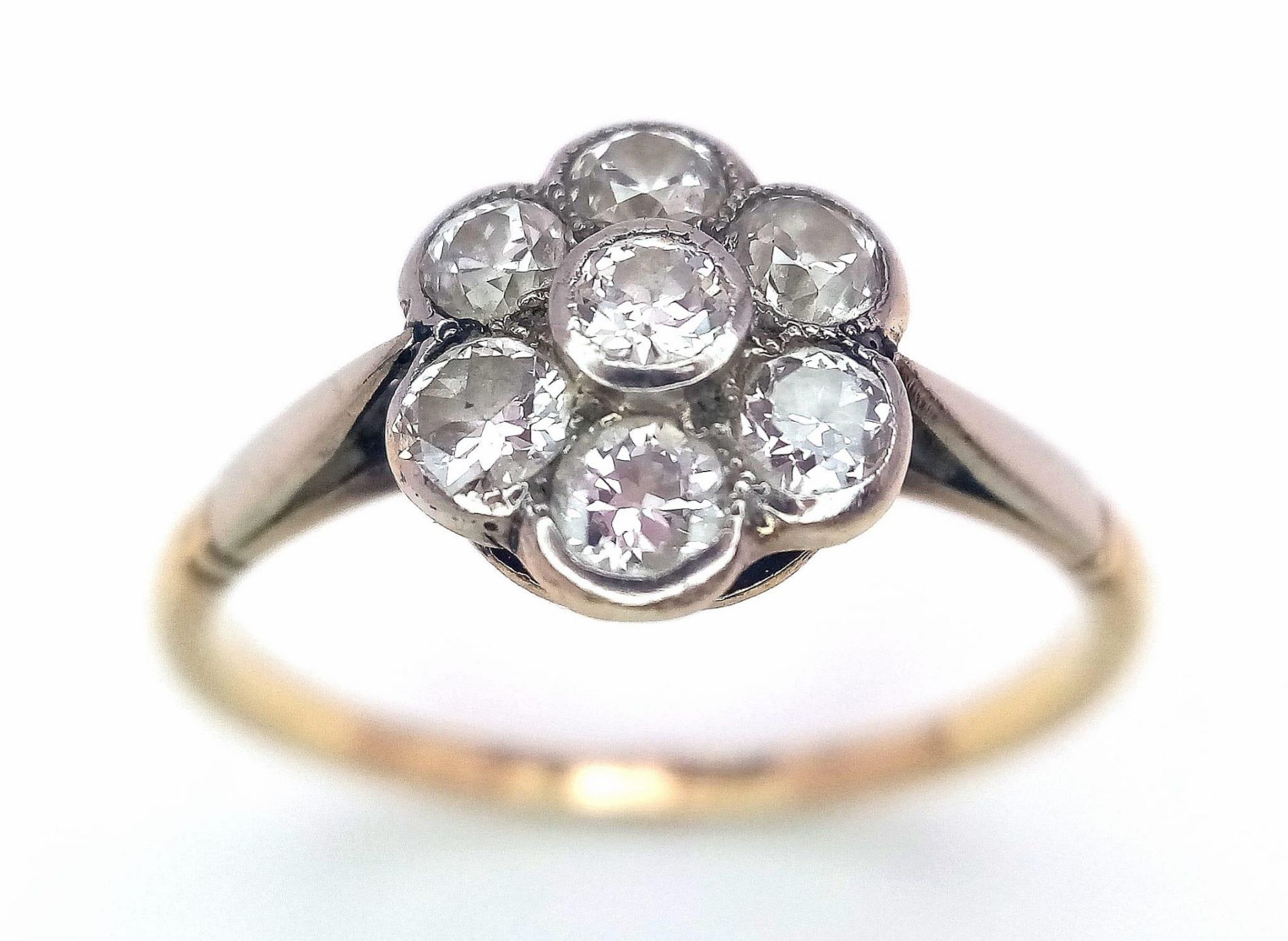 A Vintage 18K Yellow Gold Diamond Ring. Seven round cut diamonds in a floral shape. Size P. 2.52g