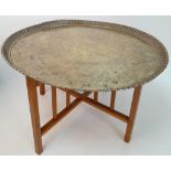 A MIDDLE EASTERN BRASS TOPPED TABLE WITH FOLDING WOODEN LEGS . 52cms TALL 76cms DIAMETER