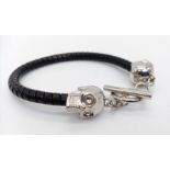 An Alexander McQueen bracelet with a twisted black leather body and two white metal sculls, made