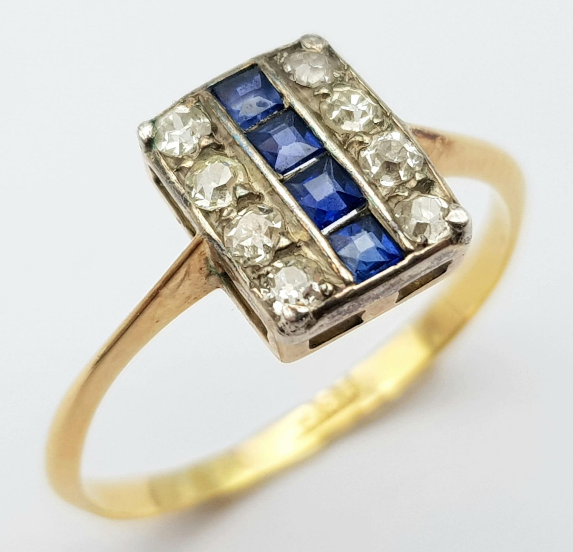 A Vintage 18K Yellow Gold Sapphire and Diamond Ring. Four square cut sapphires between eight round