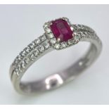 18K WHITE GOLD DIAMOND & RUBY RING, WITH A RECTANGULAR 0.30CT RUBY AND DECORATED BY A HALO