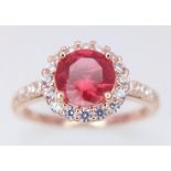 A sterling silver and rose gold plated ring with a simulated ruby surrounded by cubic zirconia.