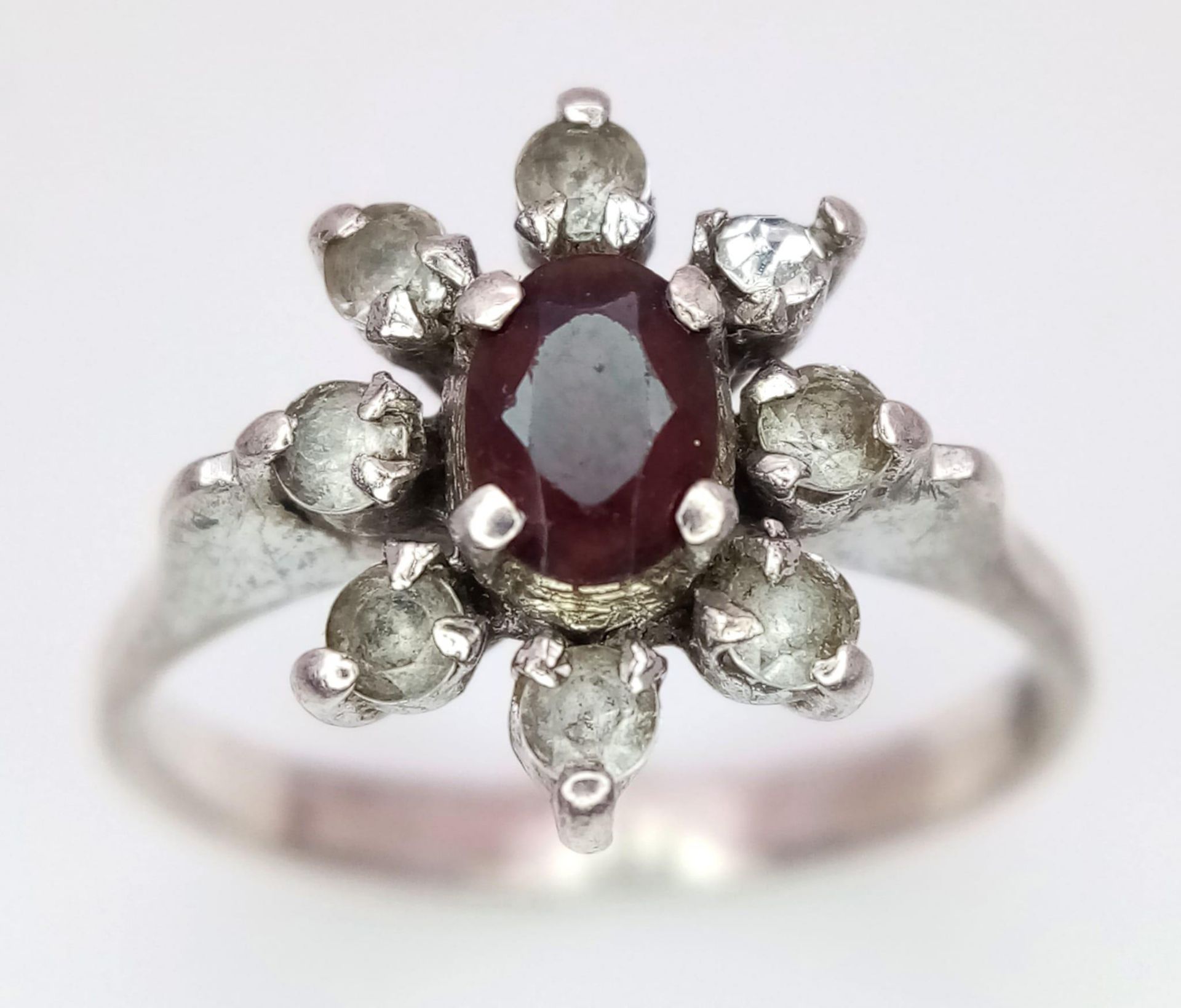 A fancy 925 silver Zirconia and Garnet floral cluster ring. Total weight 2.5G. Size K.