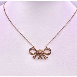 A 9KT Yellow Gold Necklace with a beautiful Bow, Pearl set Pendant. Measuring 50cm in length, this