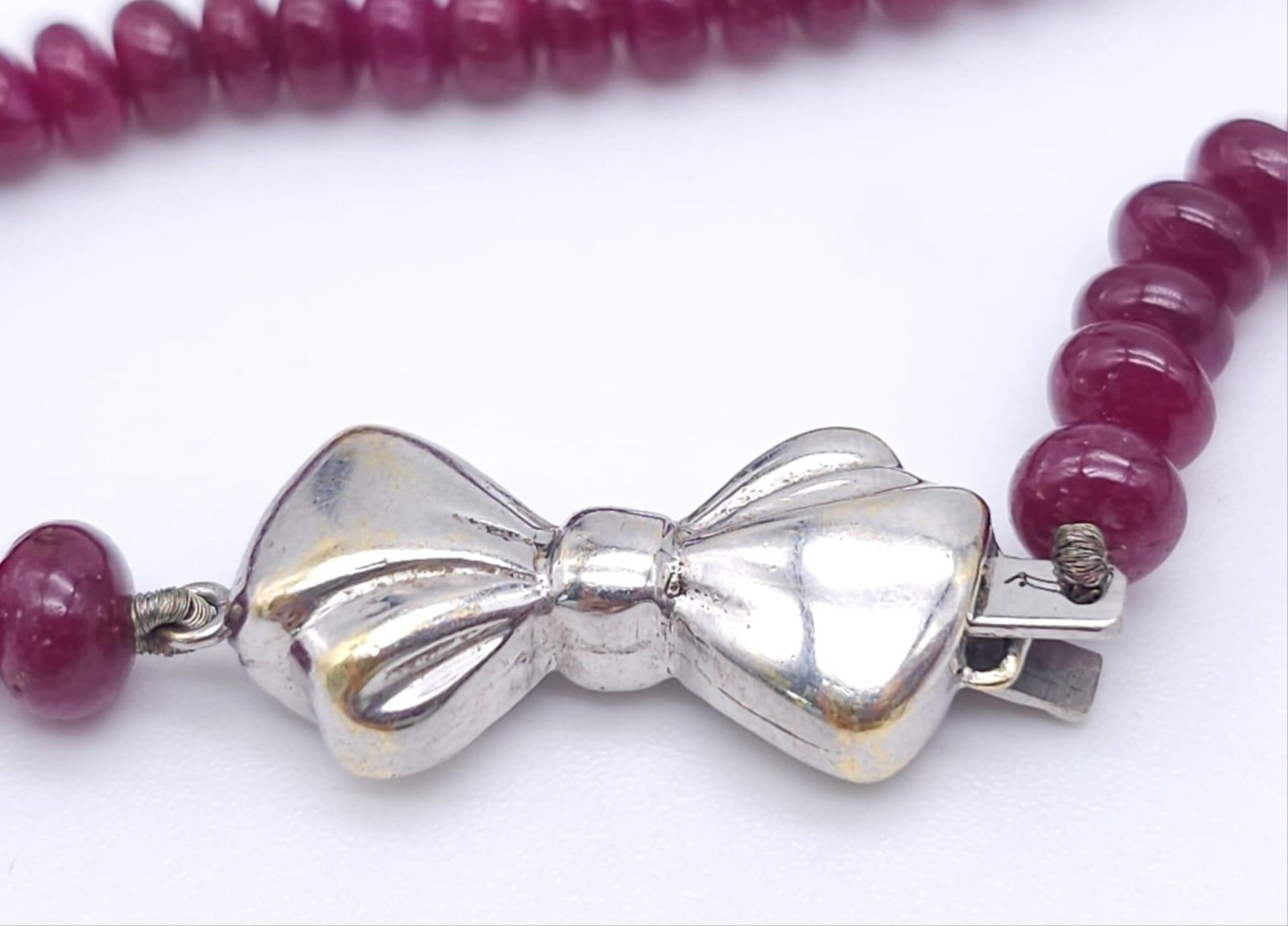 A superb graduating Ruby Red Stone Beaded Necklace with a 18kt White Gold, Diamond Set Bow Clasp. - Image 4 of 7