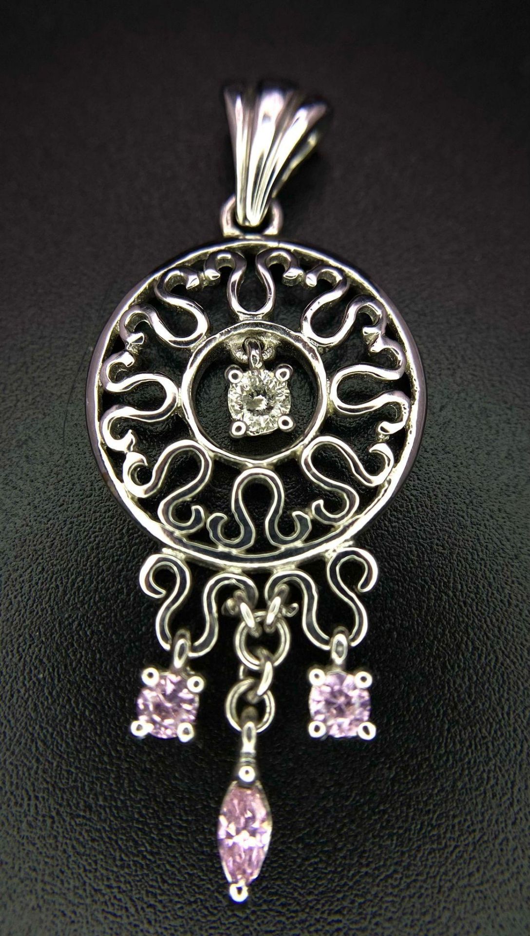 A 9K white gold diamond and pink sapphire circular articulated pendant, 2.7g, 4cm length (dia:0.