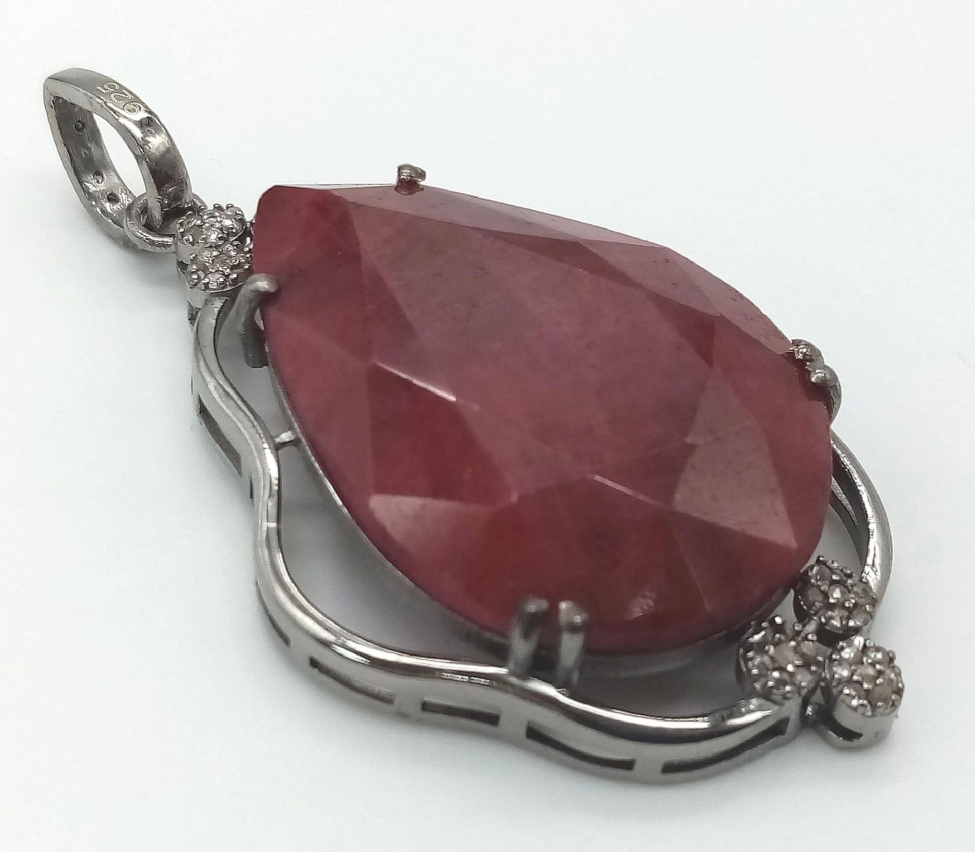 A 55.95ct Ruby Teardrop Pendant with 0.45ctw of Diamond Accents. 17.5g total weight. 5.5cm. Comes