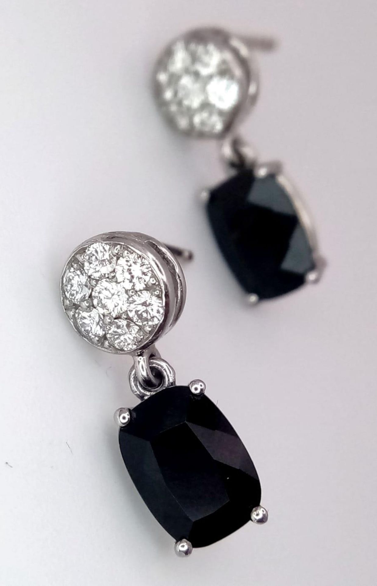 A Pair of 18K Diamond and Onyx Earrings. Diamond clusters and rectangular cut onyx. No backs. With
