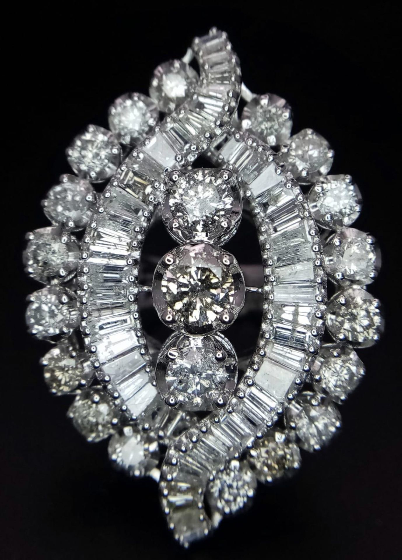 An 18K White Gold Diamond Dress Ring. This 'all seeing' diamond masterpiece begins with three