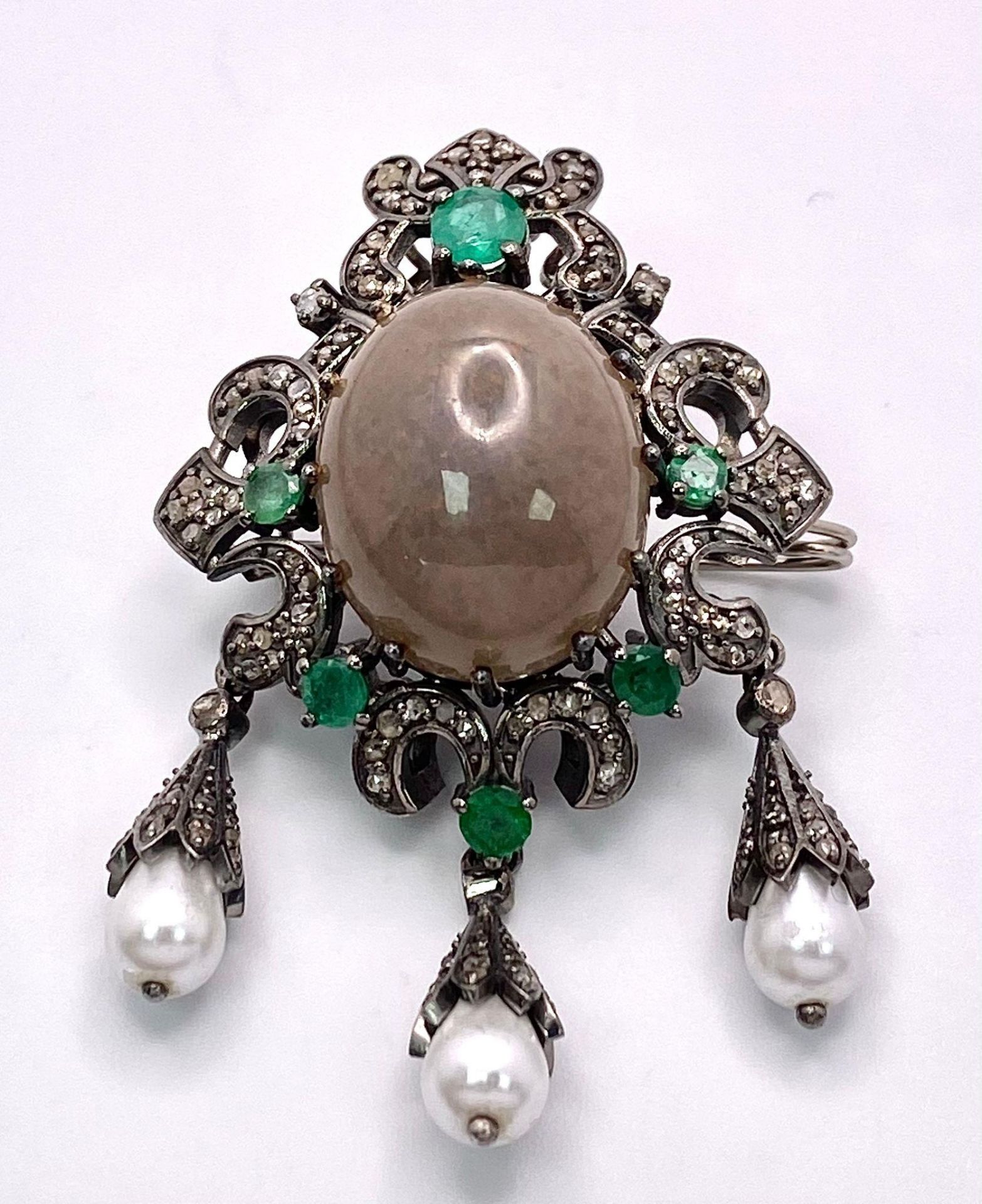 A Scintillating Opal, Emerald & Diamond, Sterling Silver (tested) Brooch. The central 6.10ct opal