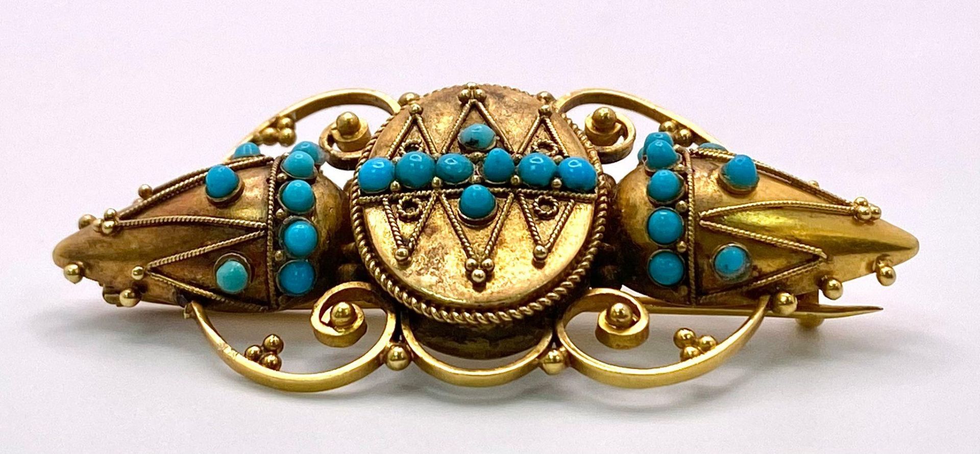 An Antique, Victorian 15K Gold and Turquoise Brooch. Scrolled and mirrored decoration. 5.5cm. 8.