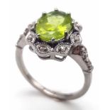 A Peridot and Diamond 925 Silver Ring. Central 2.50ct oval peridot with a diamond surround - 0.