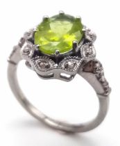 A Peridot and Diamond 925 Silver Ring. Central 2.50ct oval peridot with a diamond surround - 0.