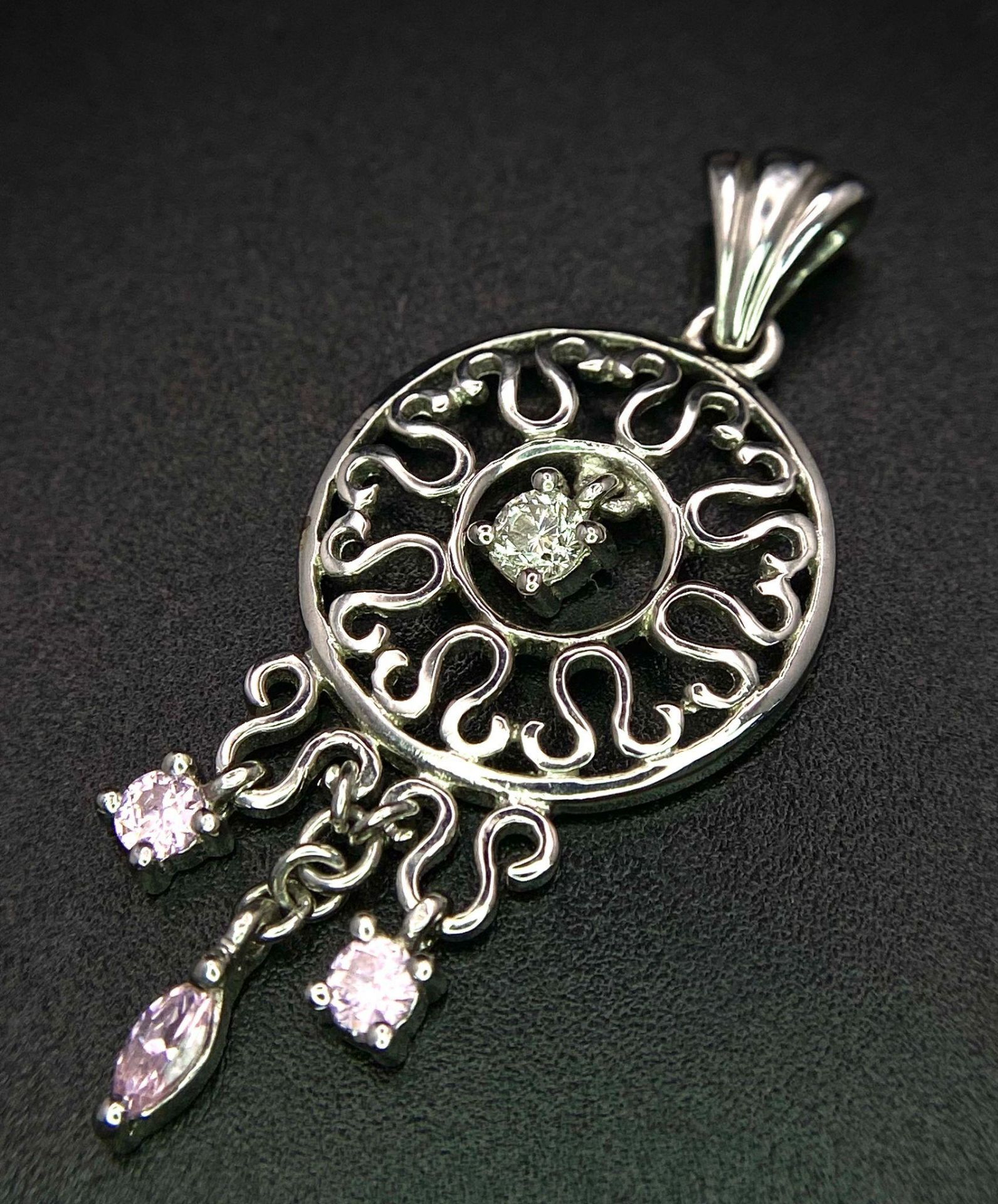 A 9K white gold diamond and pink sapphire circular articulated pendant, 2.7g, 4cm length (dia:0. - Image 2 of 4