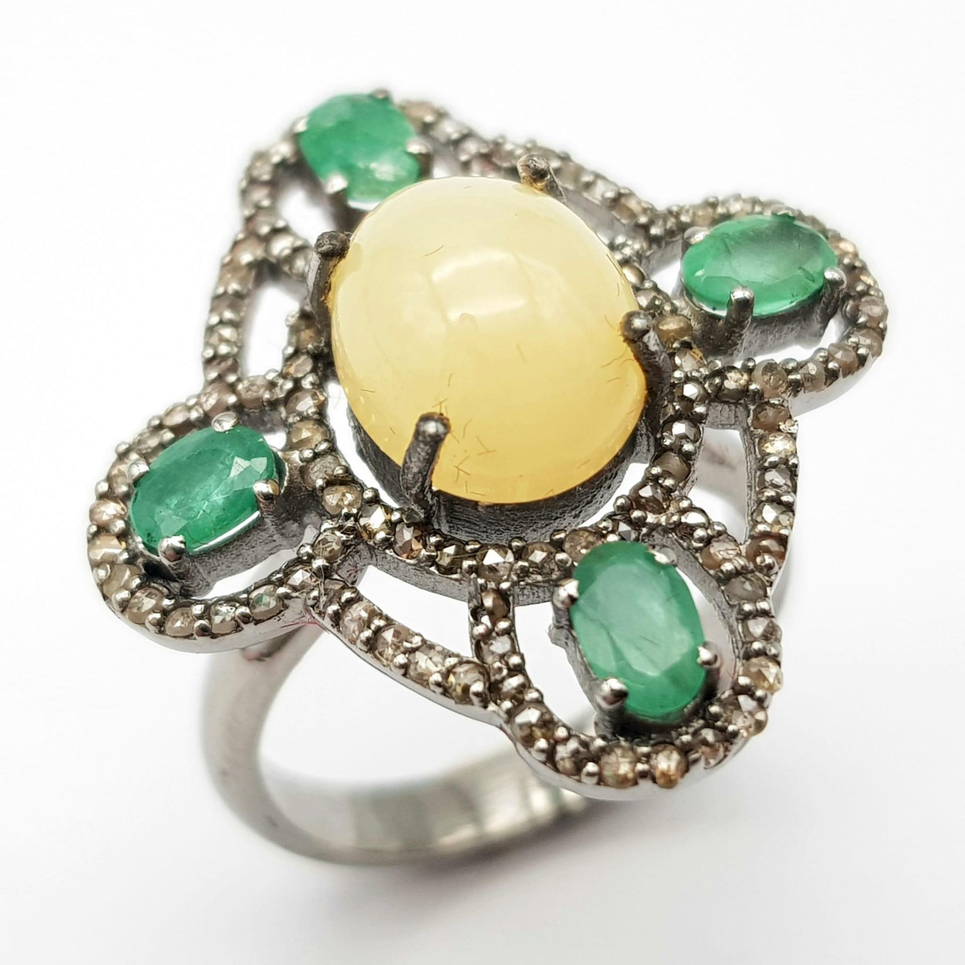 A Beautifully Designed 2.25ct Opal Ring with 0.90ctw of Emeralds and 0.85ctw of Diamond Accents.