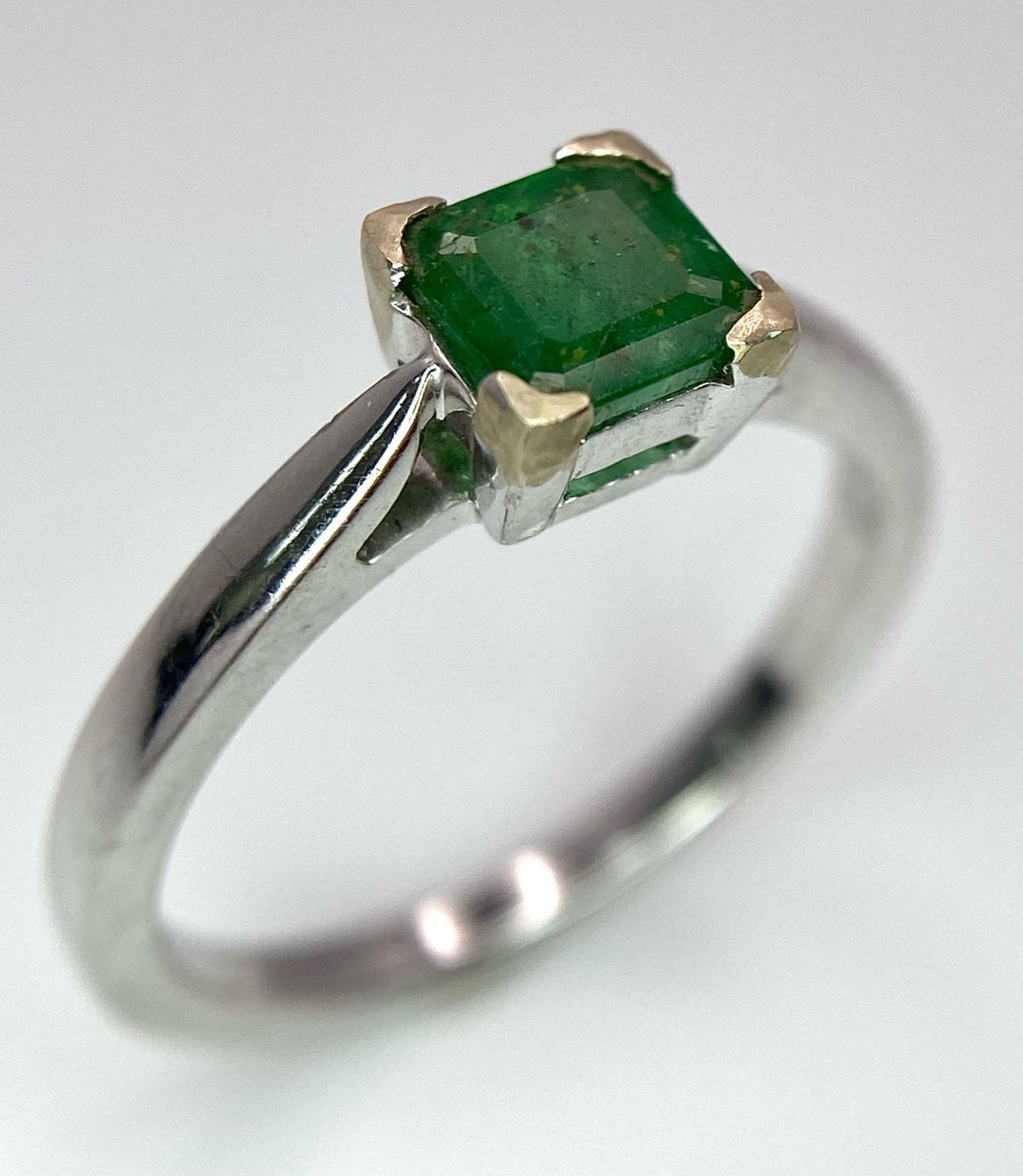 AN 18K WHITE GOLD RING WITH SQUARE EMERALD CENTRE STONE . 3.3gms size N