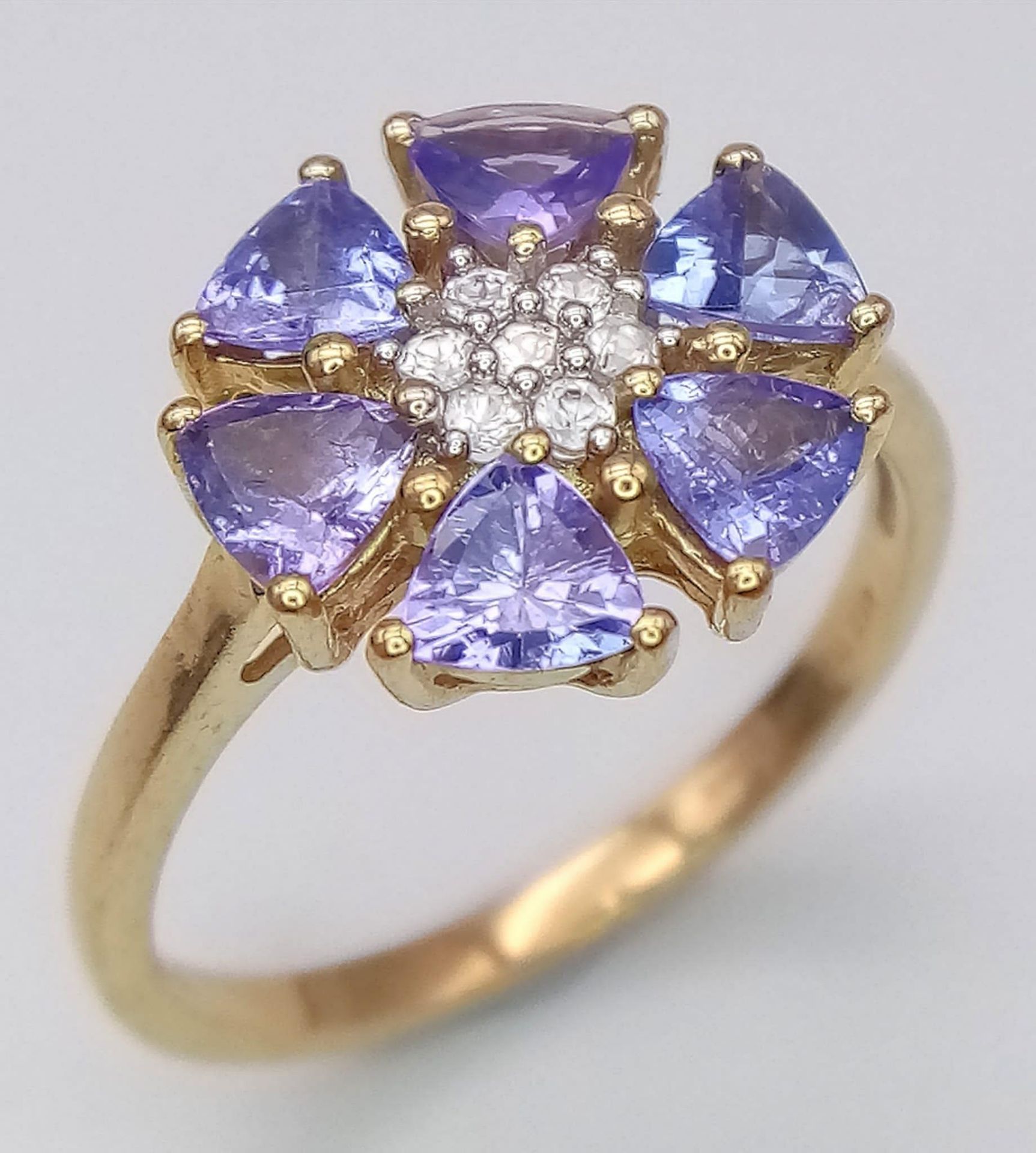 A 10K Yellow Gold Diamond and Tanzanite Floral Decorative Ring. Size R/S. 3.14g total weight.