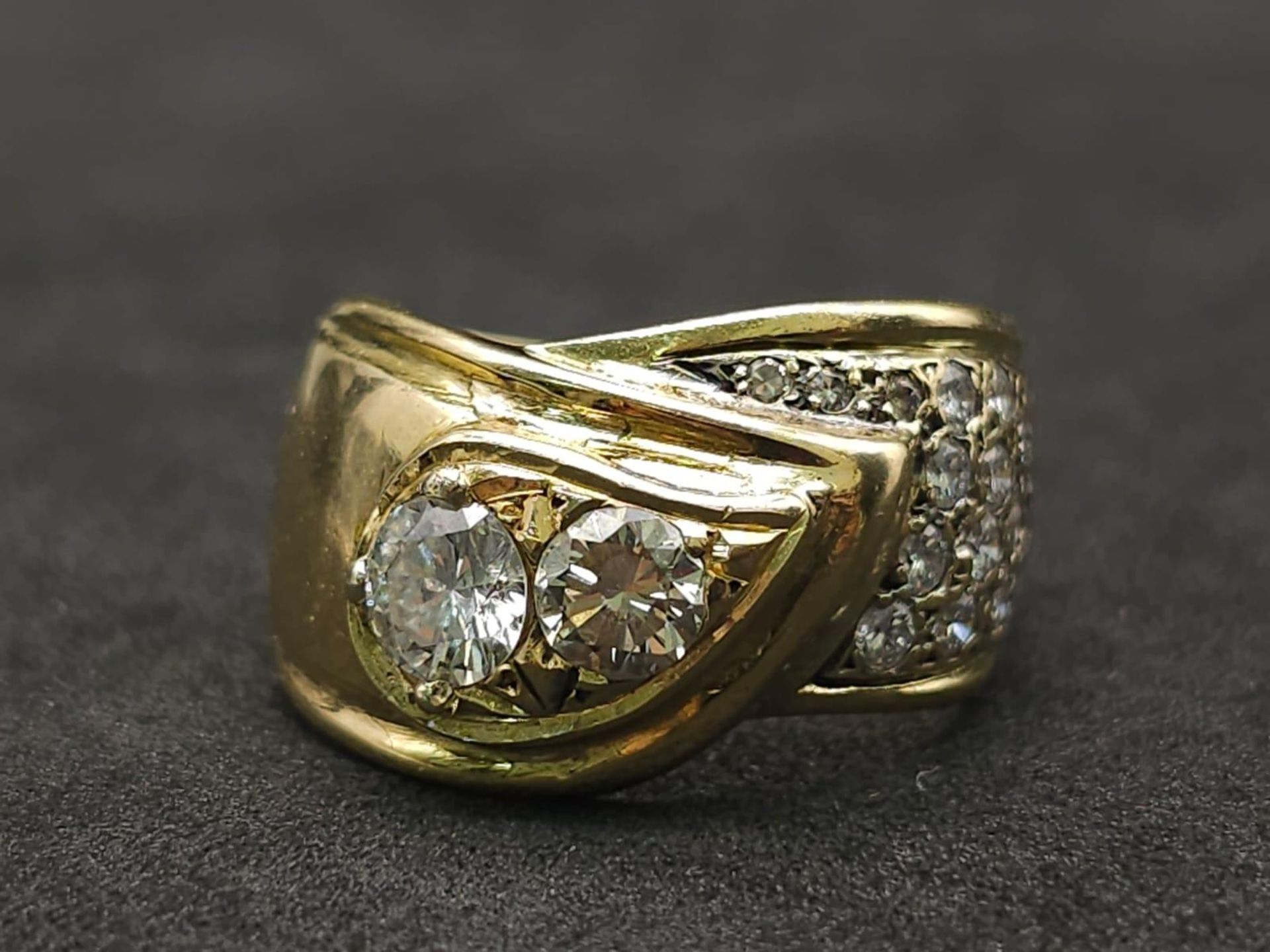 An 18kt Yellow Gold Ring with a duo of Round Cut Diamonds on one side, offset by a pavement of