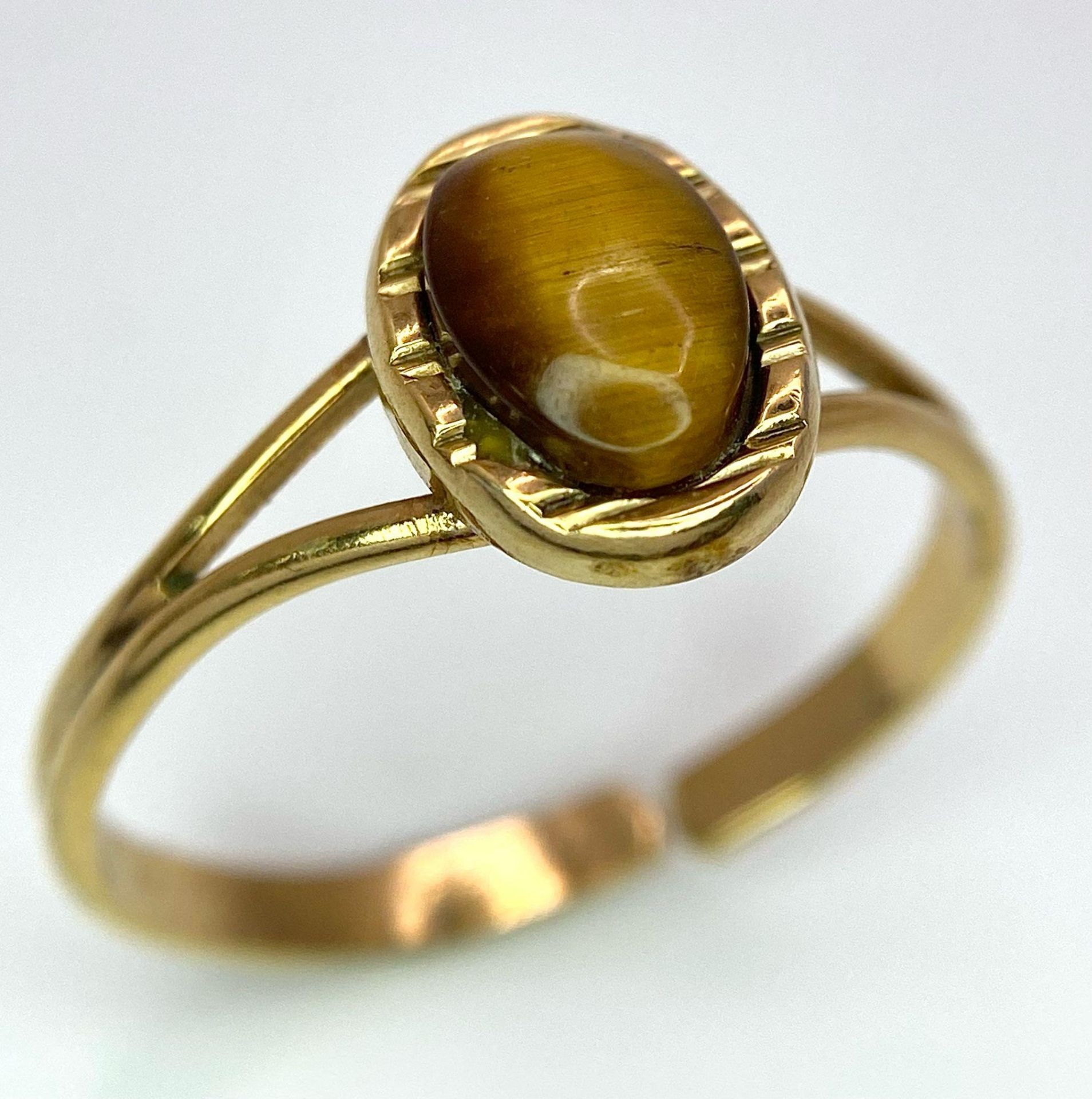 A 9K GOLD ADJUSTABLE RING WITH TIGERS EYE STONE . 2.4gms one size