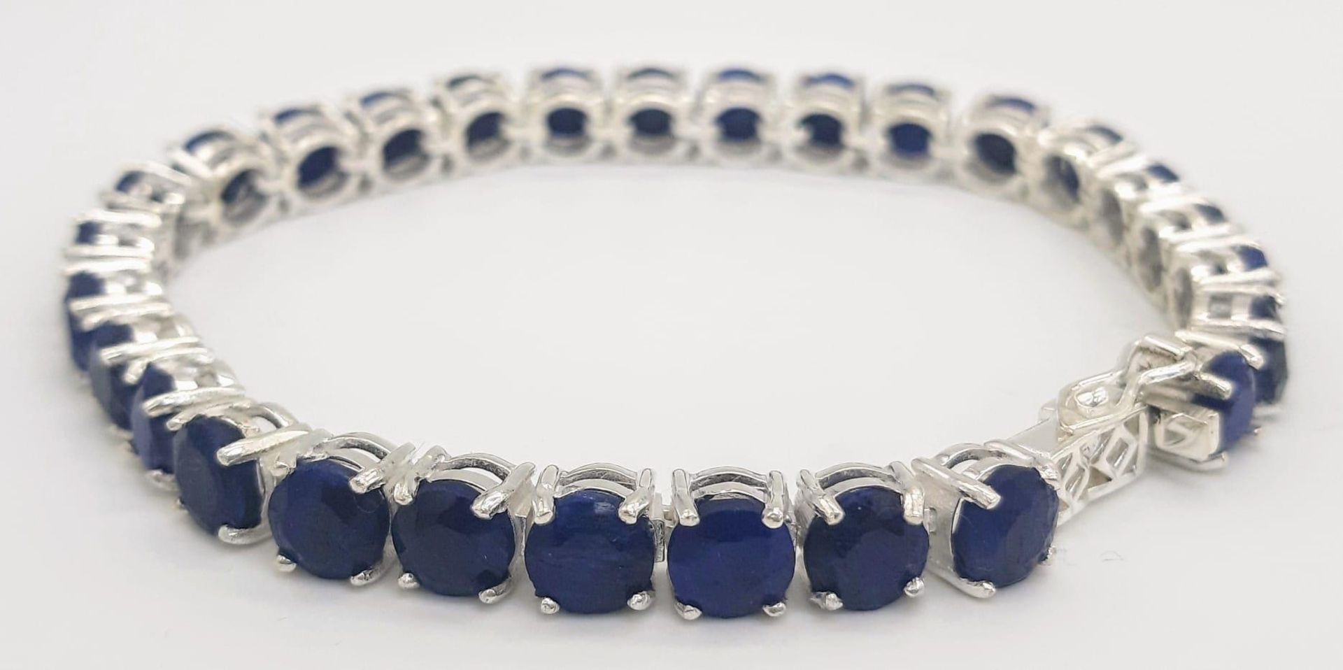 A Blue Sapphire Gemstone Tennis Bracelet set in 925 Silver. 18cm length. 19.75g total weight. Ref: - Image 2 of 5