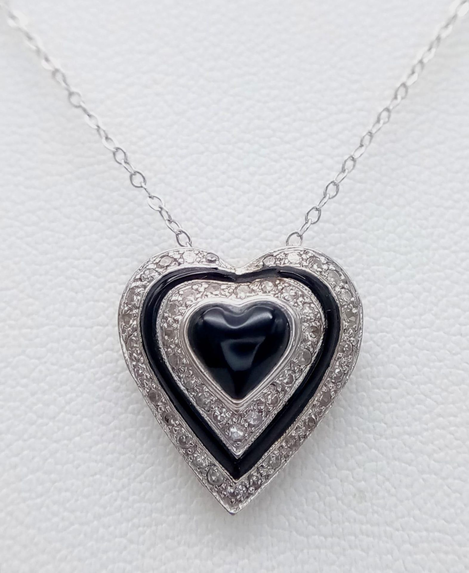 An 18K White Gold Diamond and Black Onyx Heart Pendant on a 9K White Gold Disappearing Necklace.