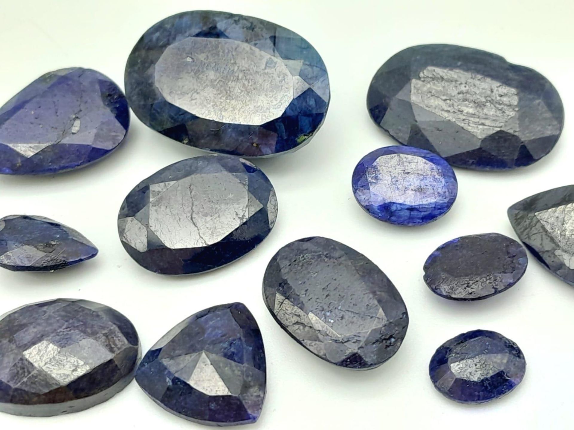 A 155.70ct Faceted Colour Enhanced Blue Sapphire Gemstone Lot - 12 Pieces, Mixed Shapes. - Image 2 of 2