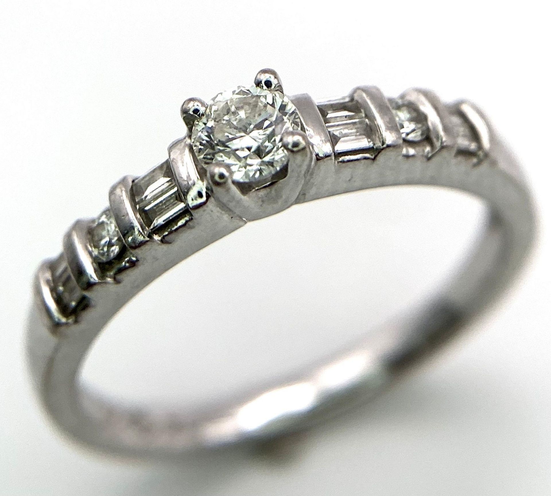 18kt White Gold, Diamond Ring. Centre Stone, 0.30ct Round Cut Diamond, is accented by shoulder