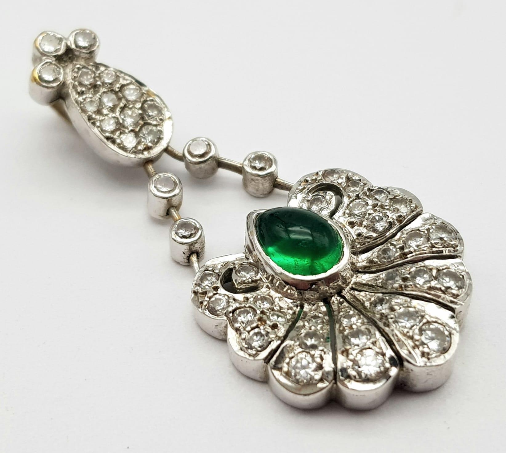 An 18K White Gold Emerald and Diamond Pendant. Central teardrop emerald with a white diamond petal