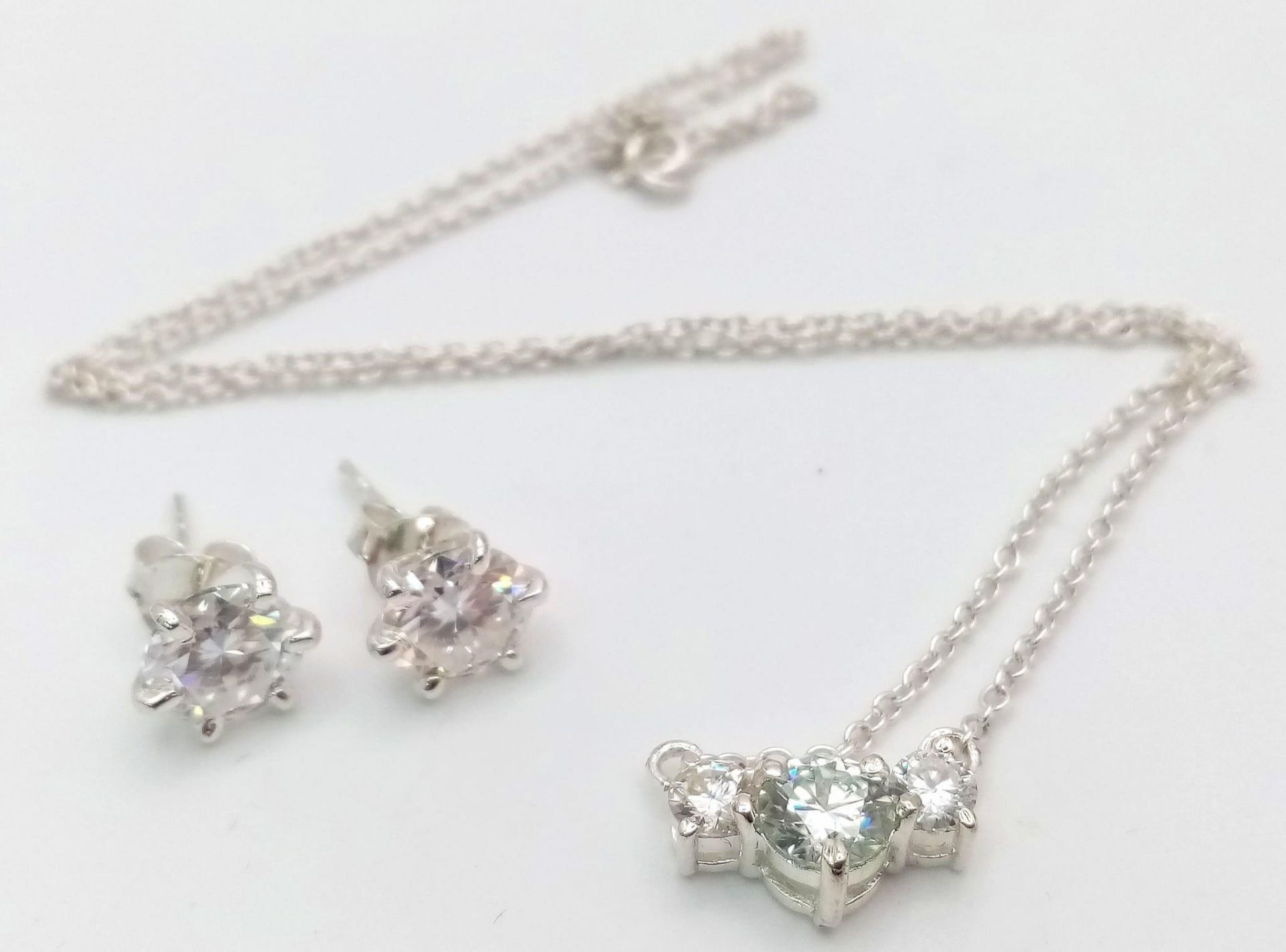 A Three Stone Moissanite Pendant on a Silver Chain and a matching pair of Moissanite Studs earrings.