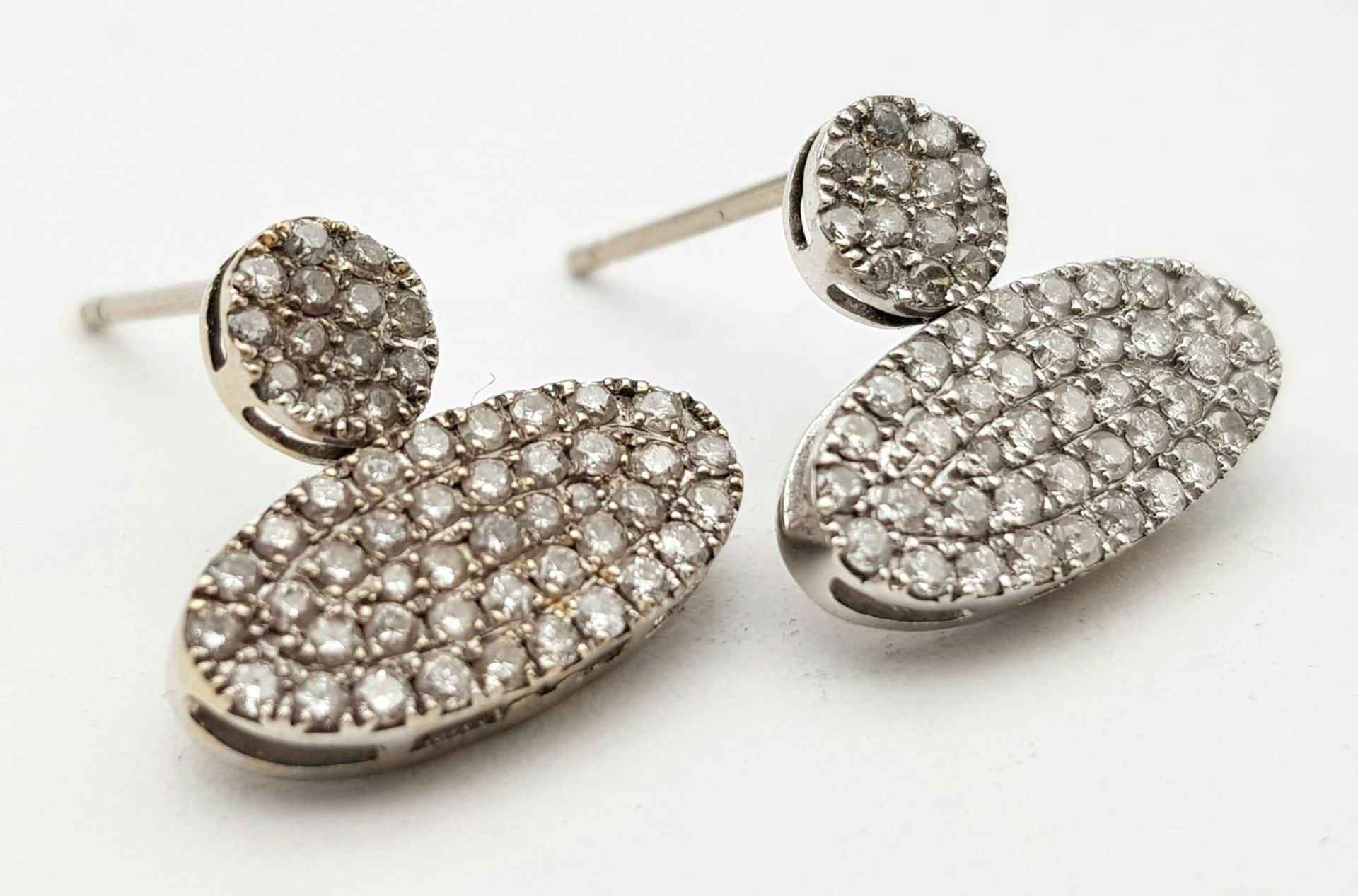 A PAIR OF DIAMOND ENCRUSTED EARRINGS SET IN PLATINUM . 2.2gms