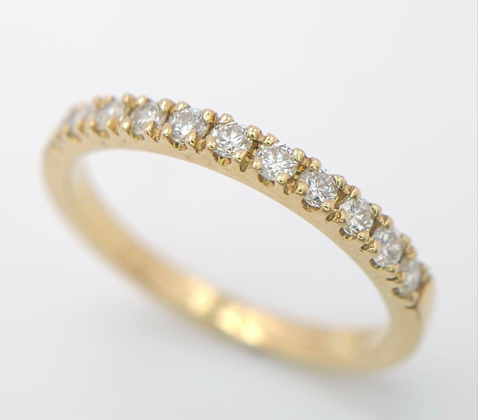 An 18 K yellow gold ring with a band of round cut diamonds, size: N, weight: 2.4 g.