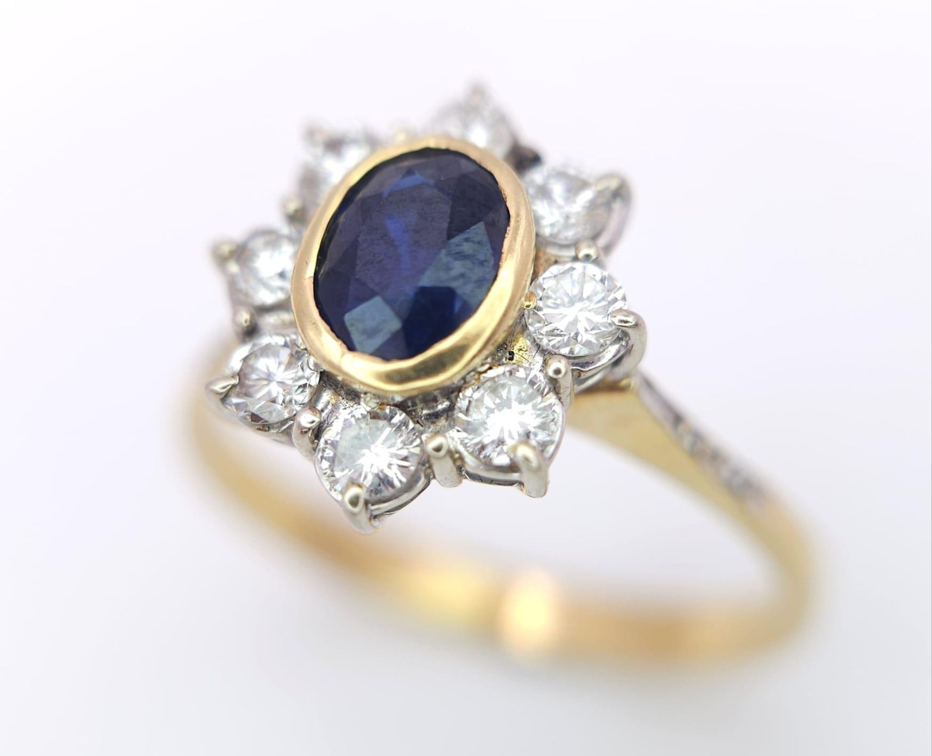 AN 18K YELLOW GOLD DIAMOND & SAPPHIRE CLUSTER RING. 0.60CTW ROUND BRIILIANT CUT DIMAONDS & 0.80CT