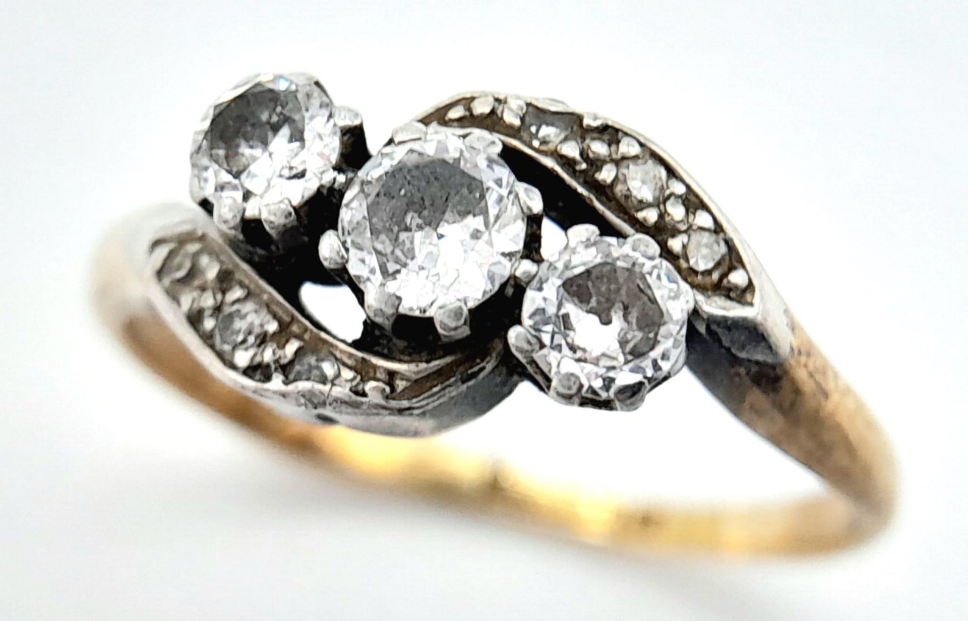 AN ANTIQUE 18K GOLD CROSSOVER STYLE RING WITH A TRILOGY OF DIAMONDS SET IN PLATINUM . 3.6gms size