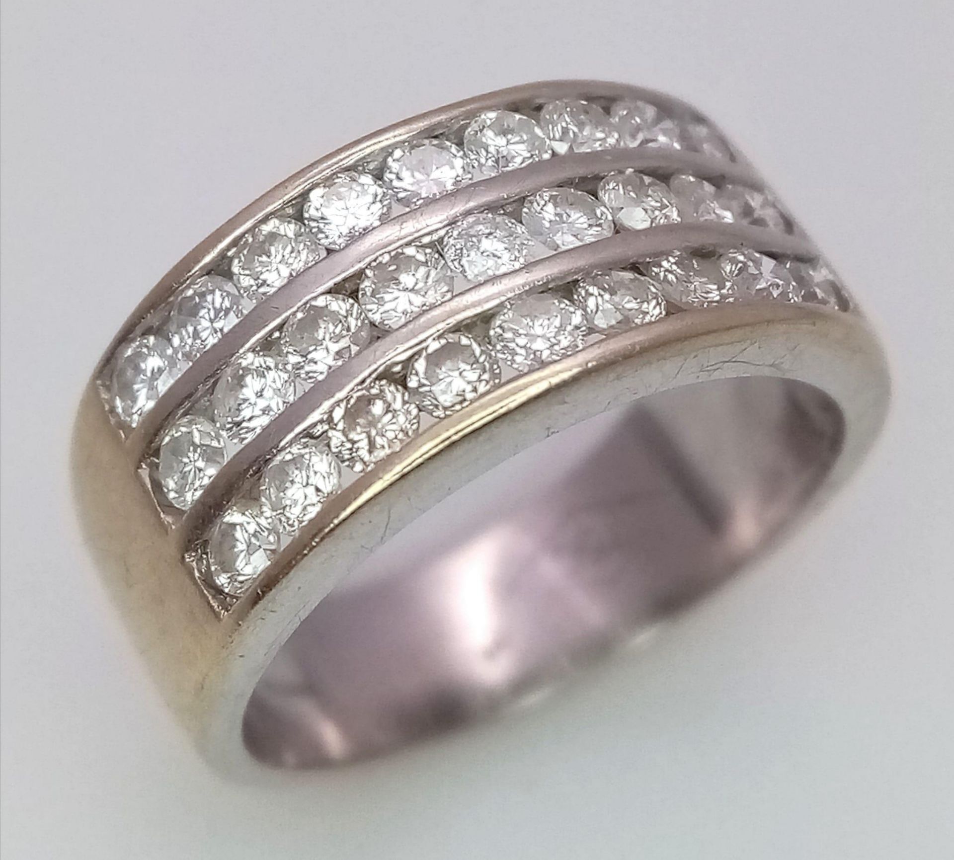 A well made 18 K yellow gold ring with three channels filled with round cut diamonds. Size: H,