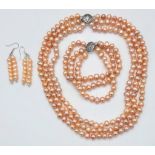 A fashionable three strand of high quality, natural pink pearls necklace, bracelet and earrings