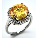 A sterling silver ring with a large round cut yellow moissanite (5 carats), surrounded by a halo