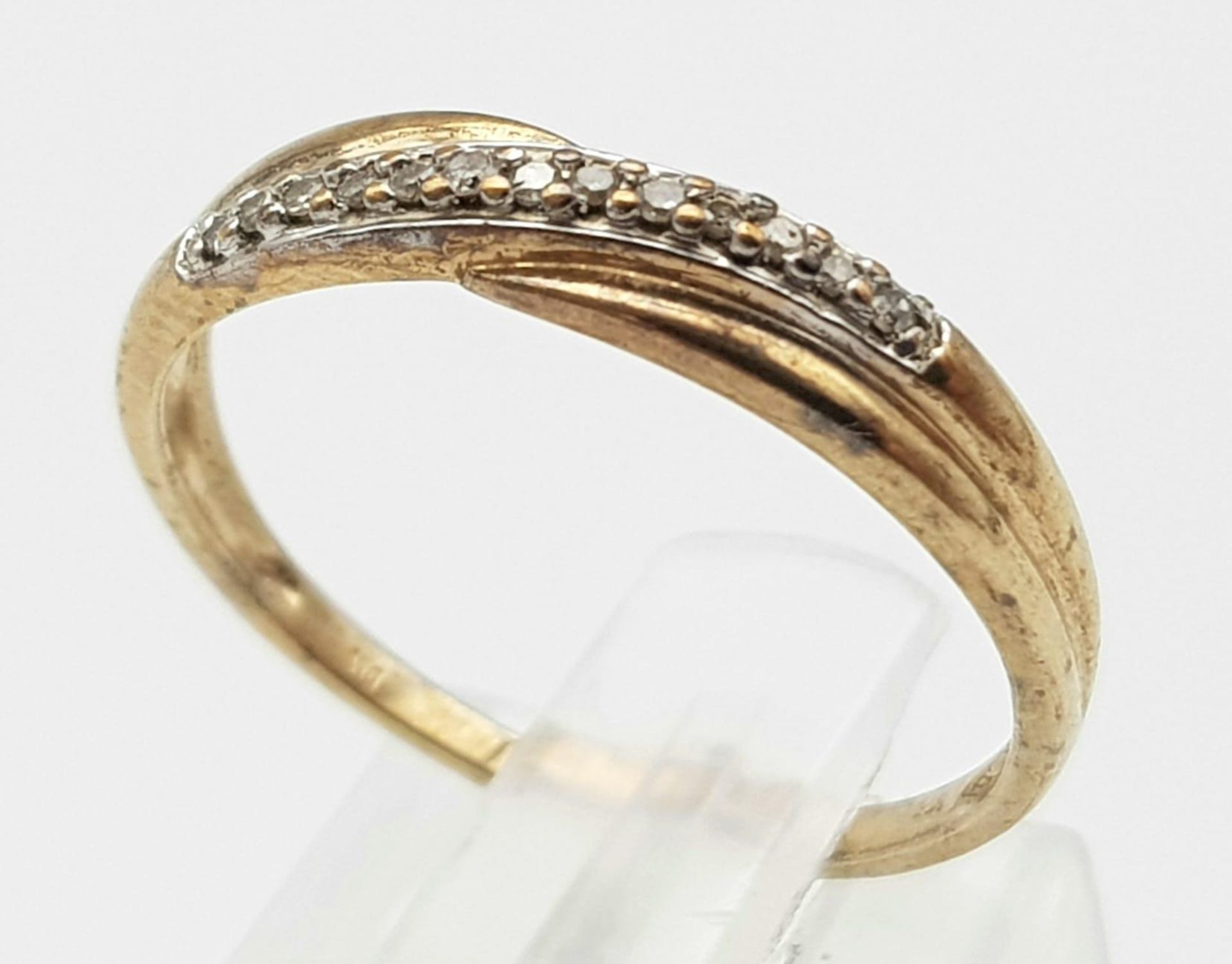 A 9K Yellow Gold Diamond Crossover Ring. Size M. 1.27g weight.