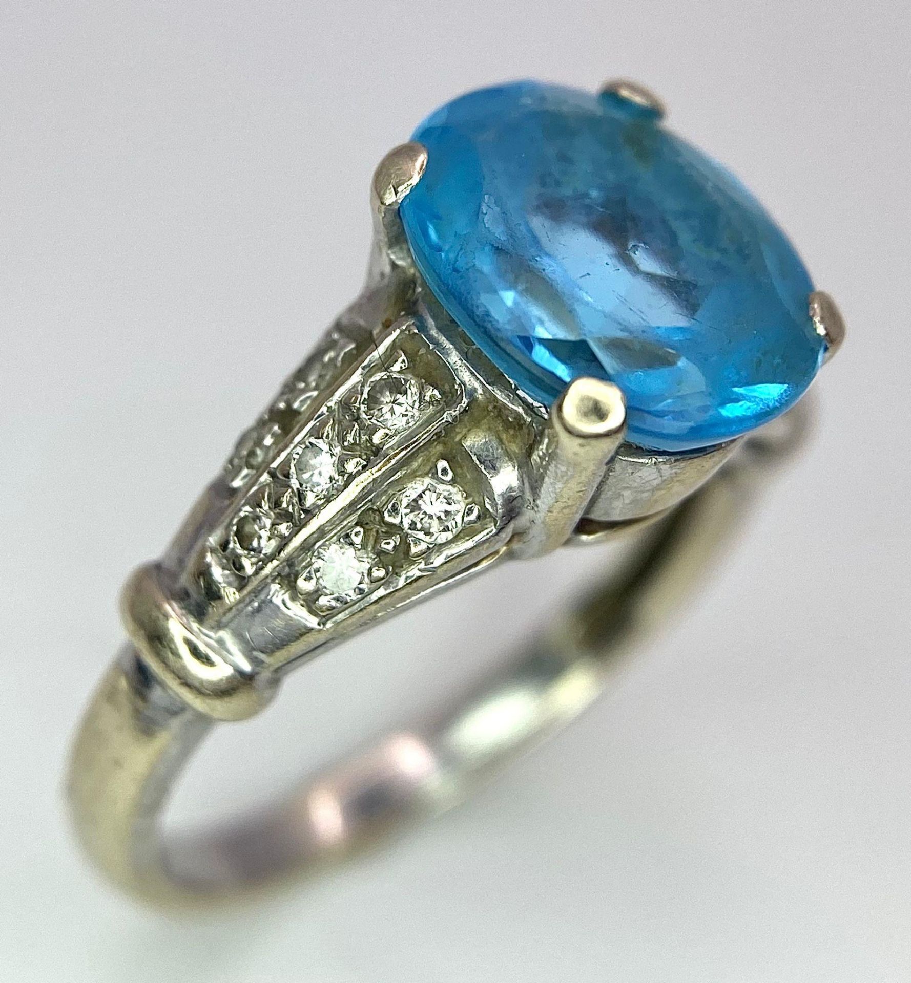 A vintage, 9 K white gold ring with a large, oval cut, vivid blue aquamarine and three bands of - Image 2 of 5