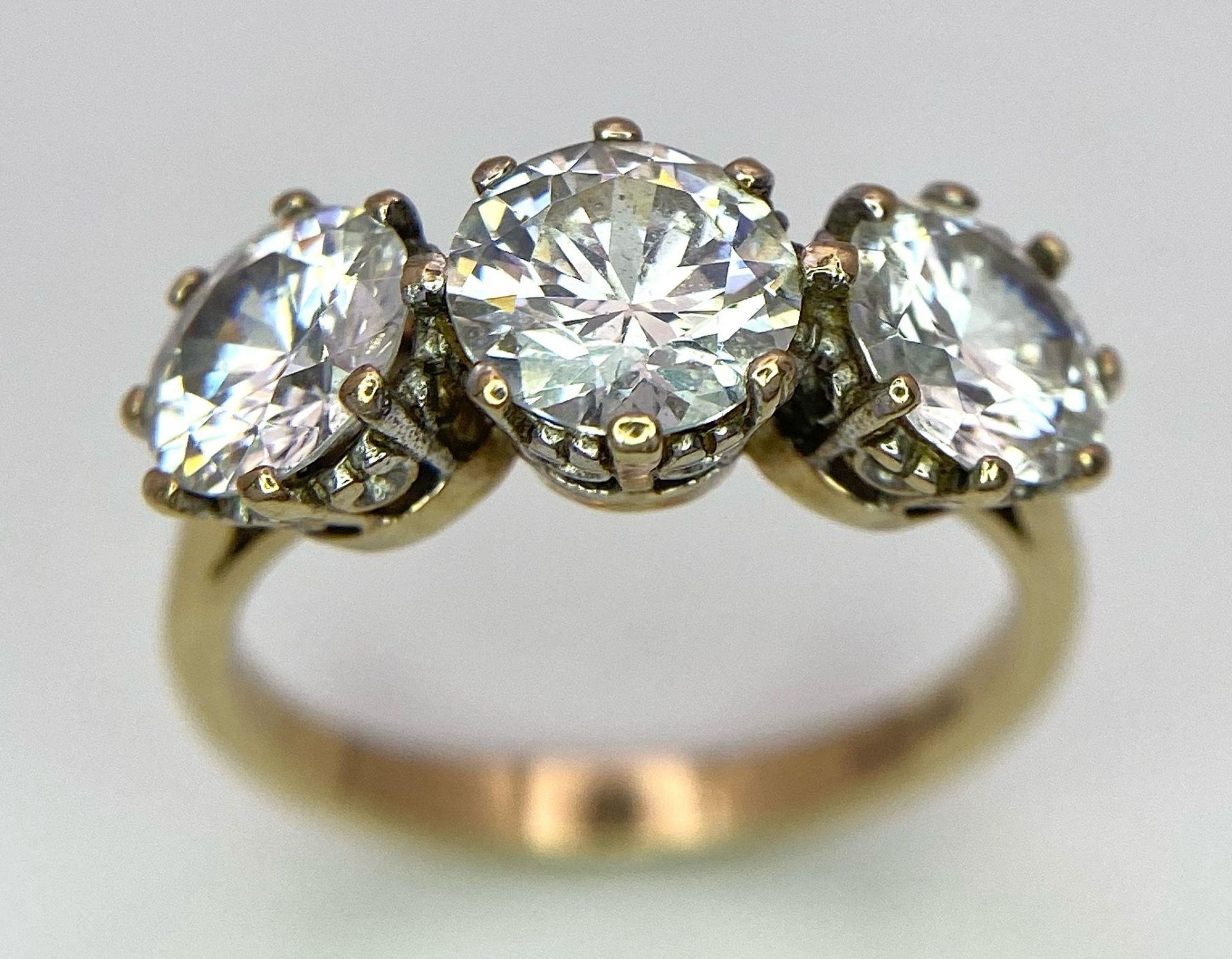 A 9K STONE SET RING WITH A TRILOGY OF SPARKLING ZIRCONIA STONES . 4.2gms size O