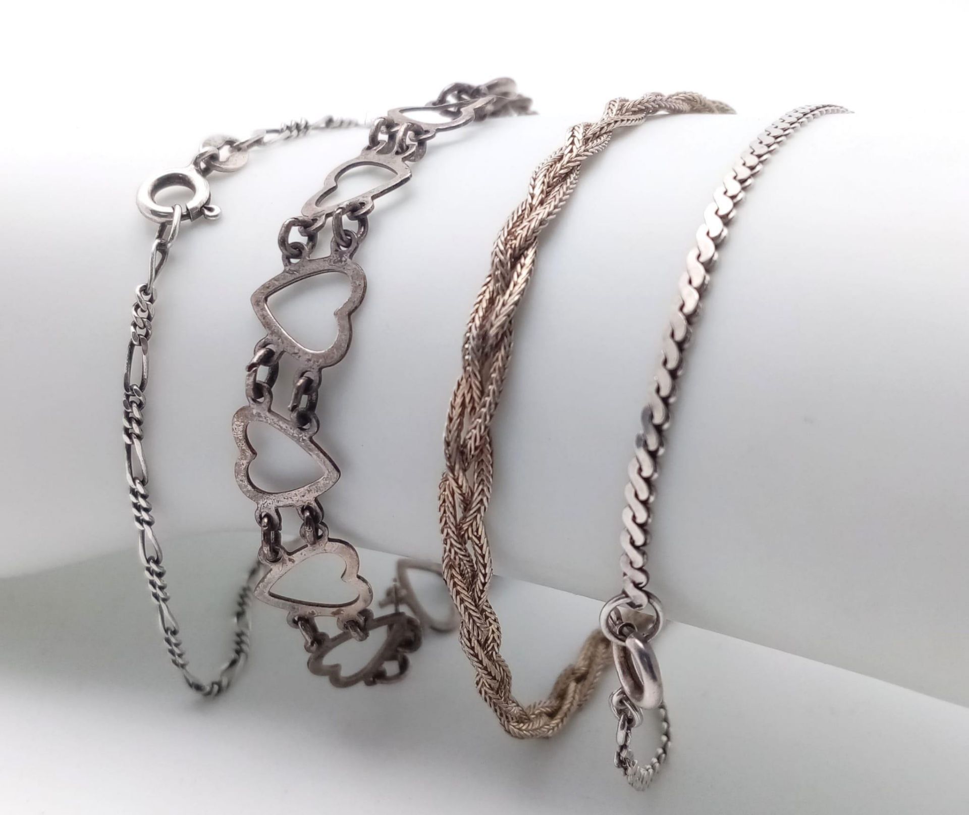 A collection of 4 stylist sterling silver bracelets include a figaro link, twisted, heart link and