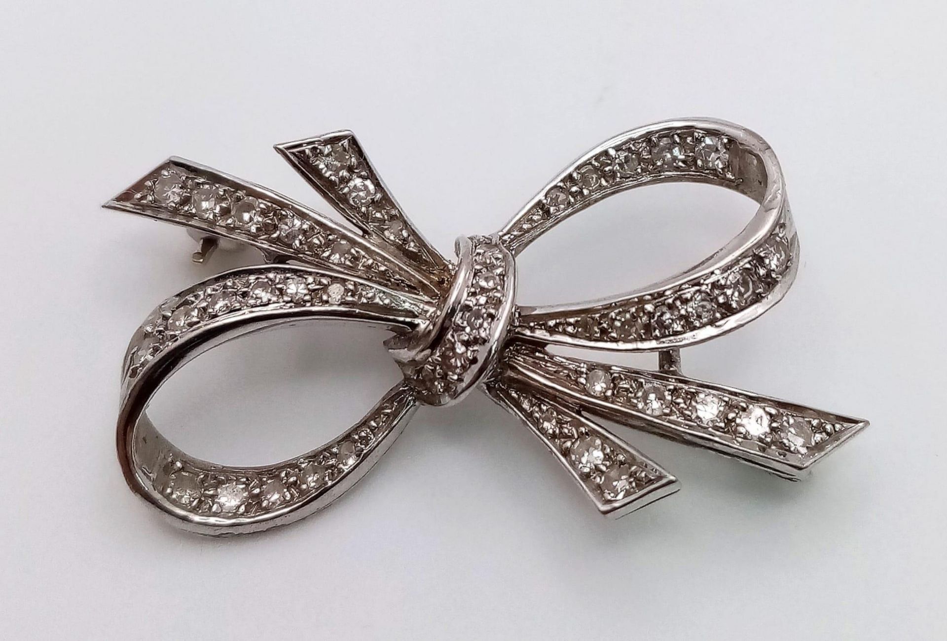 An Art Deco Style Platinum and Diamond Brooch. 1.2ctw of encrusted diamonds in a bow form. 4cm. 5.7g