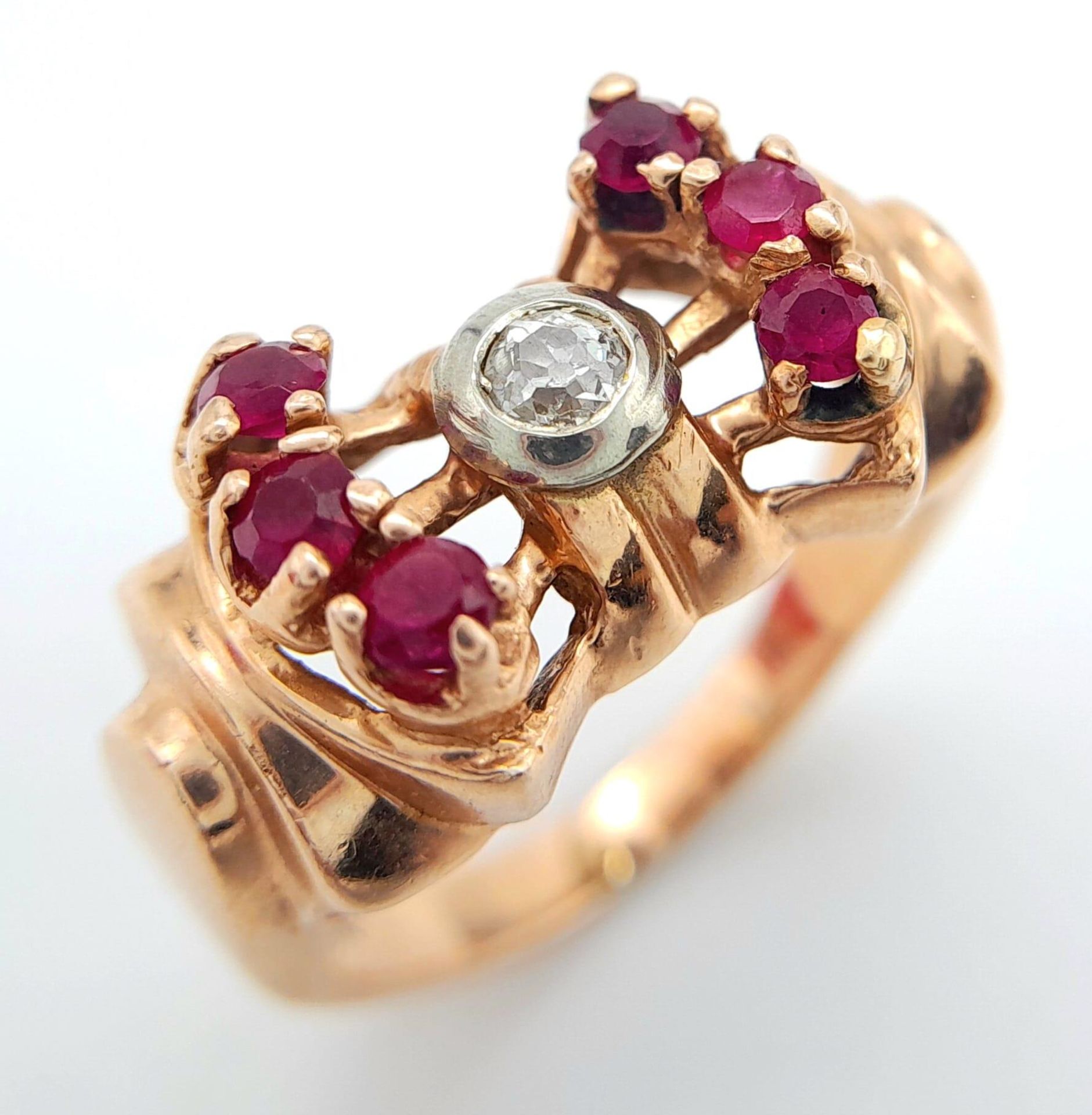 A 14K ROSE GOLD DESIGNER RING WITH CENTRAL DIAMOND FLANKED BY RUBIES . 8.1gms size L