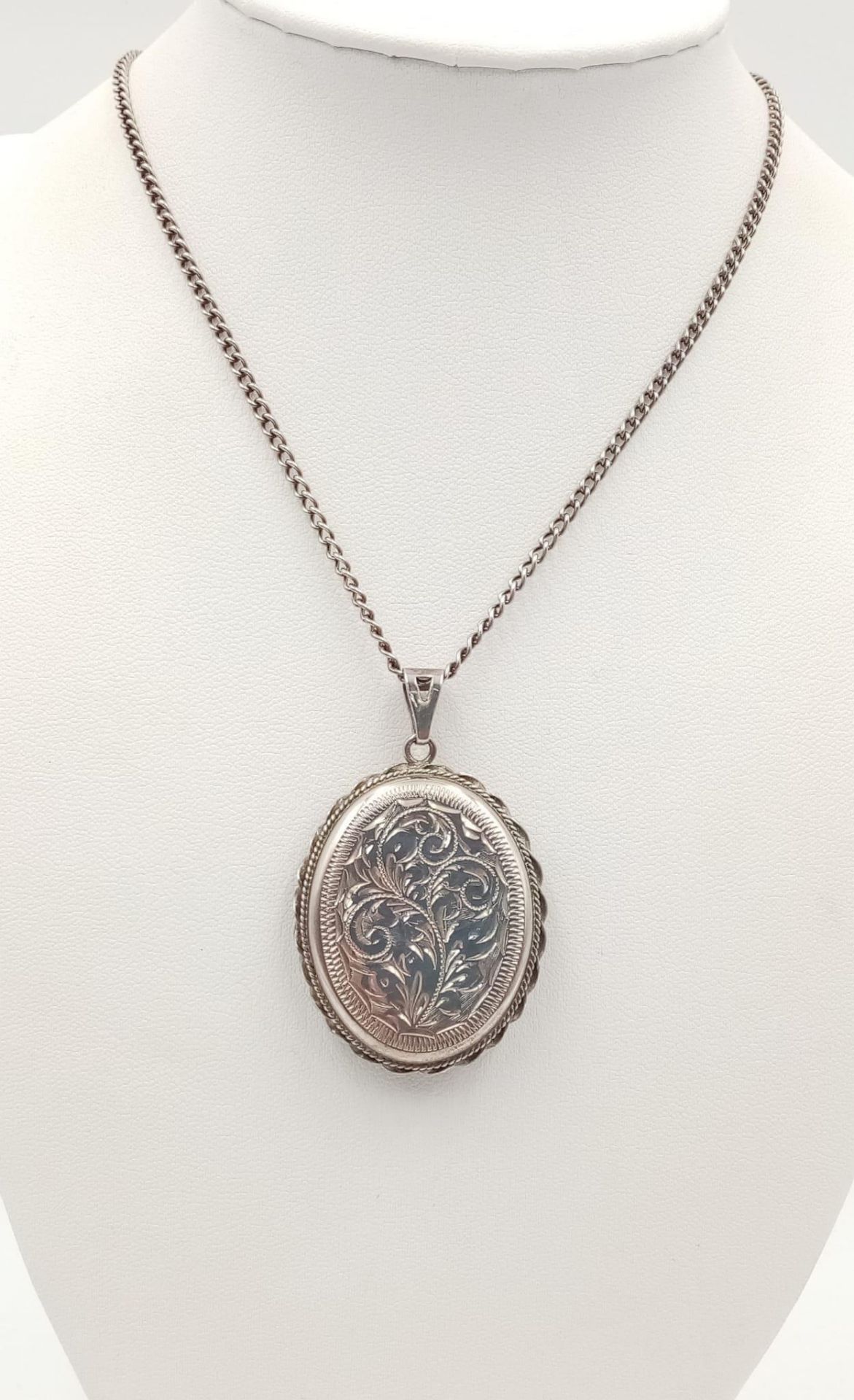A vintage sterling silver floral motif locket pendant on silver chain. Full Birmingham hallmarks,
