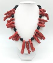 An exotic looking black onyx necklace adorned with large natural red coral pieces from South